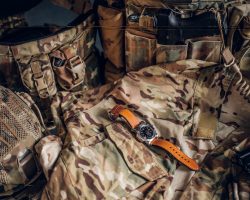 Still life with nice watch and military uniform with typical camo pattern.